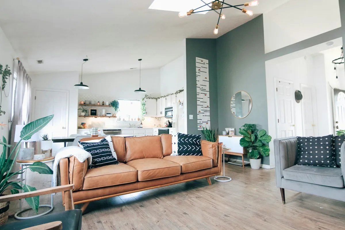 A light filled living room with a sofa and leafy houseplants