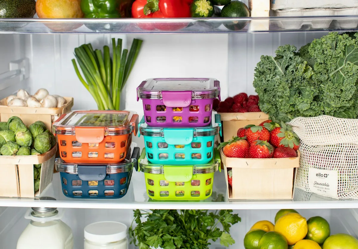 Stacked reusable food containers and fresh produce inside a refrigerator