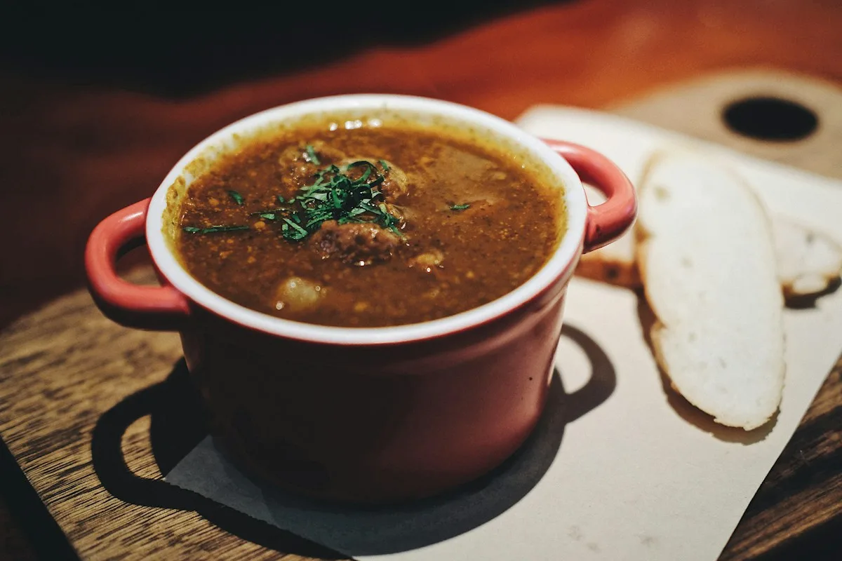 A red handled bowl of soup served with bread
