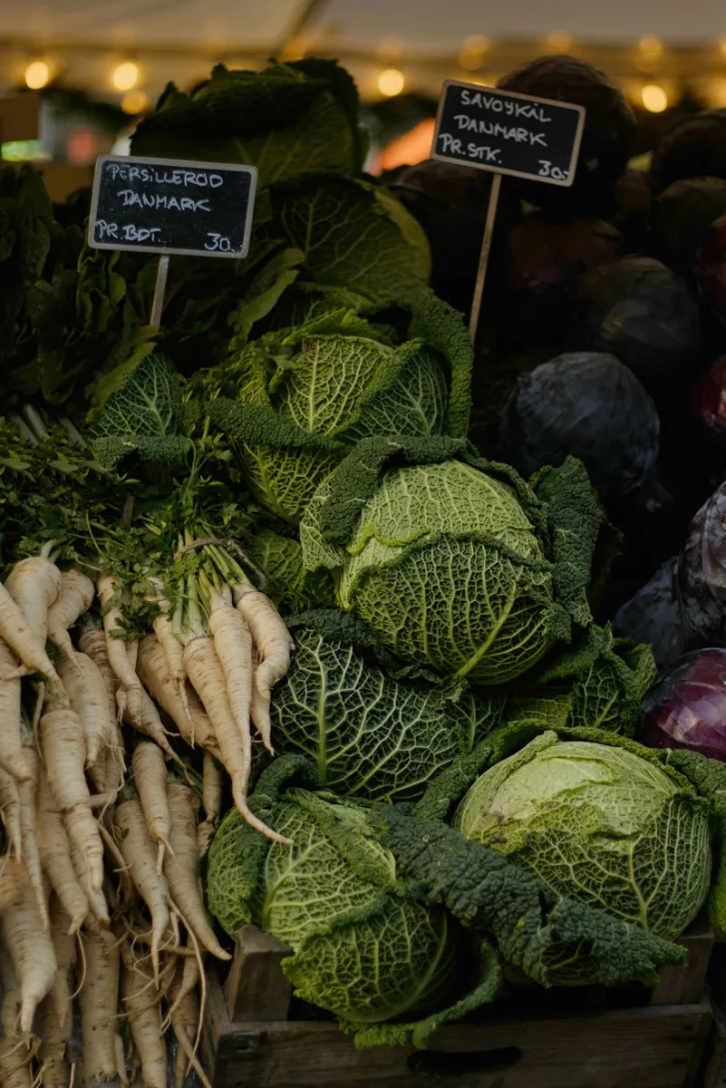 Fresh cabbages and pale root vegetables displayed at a market